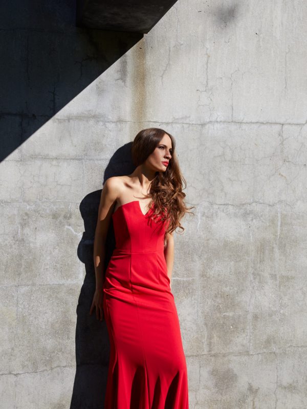 Chelsea Randall Pianist in red dress leaning on concrete wall